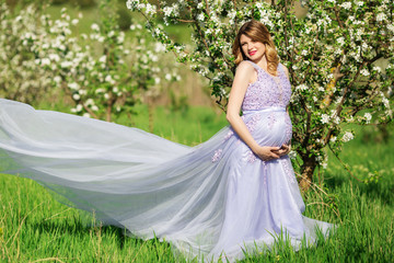 Fototapeta premium Happy pregnant woman in apple blossom garden