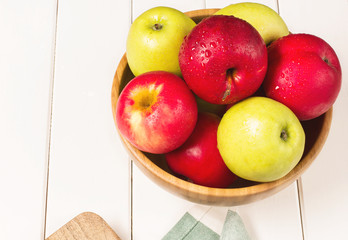 Red and green apples on a white wooden background, horizontal, soft focus, top view
