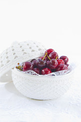 Cerezas rojas en bol con fondo blanco, vertical