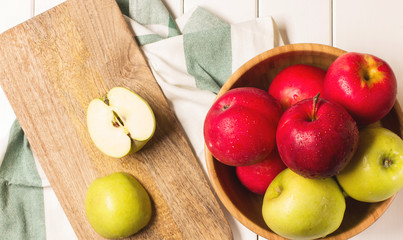 Red and green apples on a white wooden background, horizontal, soft focus, top view
