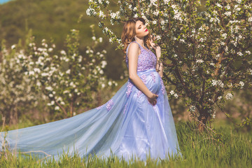 Happy pregnant girl in blossom spring garden