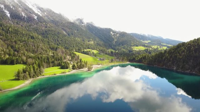 Aerial: flying over Hintersteiner Mountain lake with clear water in Austria and beautiful cloud reflections
