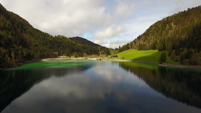 Aerial: flying over Hintersteiner Mountain lake with clear water in Austria and beautiful cloud reflections