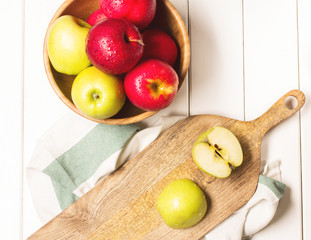 Red and green apples on a white wooden background, horizontal, soft focus, top view