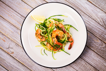Shrimp with zucchini noodles. Prawns with vegetables and lemon. View from above, top studio shot