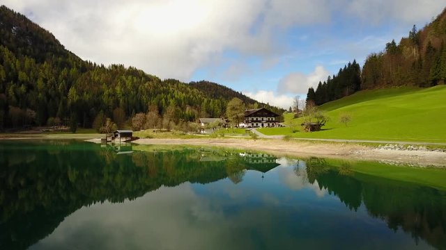 Aerial: flying over Hintersteiner Mountain lake with clear water in Austria and beautiful cloud reflections