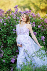 Obraz na płótnie Canvas Pretty pregnant woman in blossom lilac garden