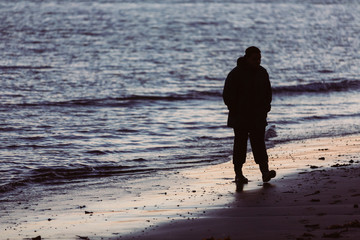 Man walking on beach at night looking into the sea with desire