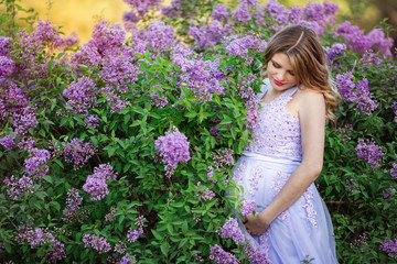 Pretty pregnant woman in blossom lilac garden