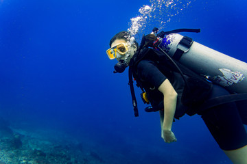 Woman tourist diver in descent to reef scuba diving under water