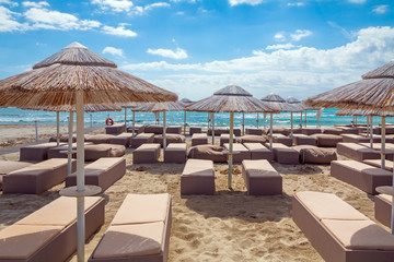 Sunbeds with umbrellas on white sand beach in Villasimius beach, Sardinia island, Italy