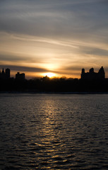Fototapeta na wymiar Sunset and silhouette buildings over lake