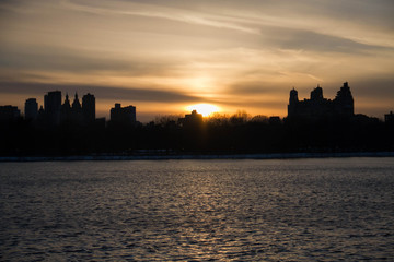 Fototapeta na wymiar Sunset and silhouette buildings over lake, New York