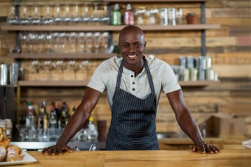 Portrait of smiling waiter standing at counter