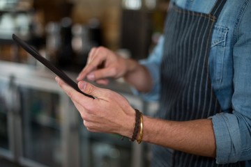 Mid section of waiter using digital tablet