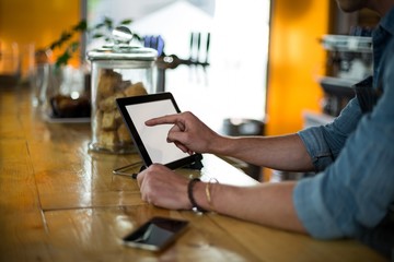 Waiter standing at counter using digital tablet