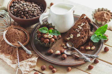 Piece of chocolate cake, mint leaves, hazelnuts and jar with milk