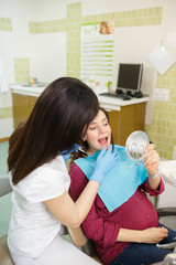 Dentist showing teeth problems to pregnant woman