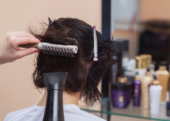 Fototapeta premium The hairdresser dries her hair a brunette girl in a beauty salon.