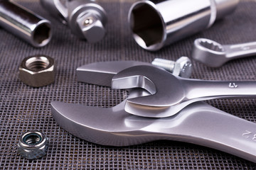 Set of  wrenches, nuts and bolts on a metal background.