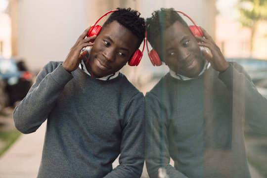 African american man with headphones listen music in city