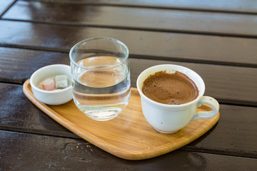 Turkish coffee on the wood with glass of water and turkish delights
