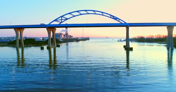 Flying low over river and under scenic Leo Frigo Memorial Bridge in slow motion, at dawn.