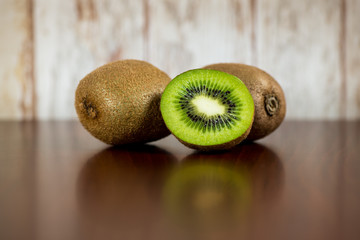 Half kiwi and two kiwi, wooden background.
