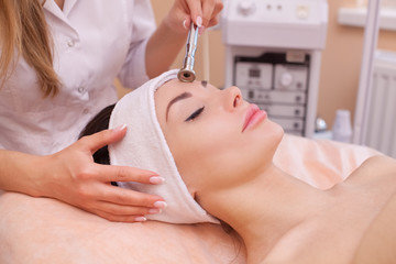 The doctor-cosmetologist makes the procedure Microdermabrasion of the facial skin of a beautiful, young woman in a beauty salon.Cosmetology and professional skin care.