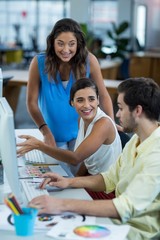 Graphic designers interacting while working on personal computer