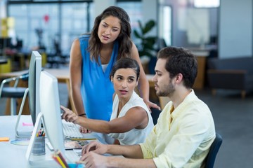 Graphic designers interacting while working on personal computer