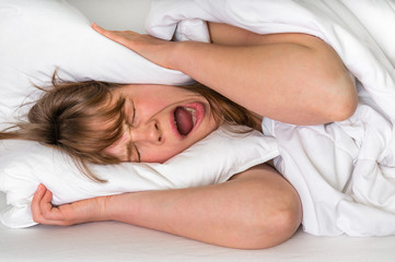 Obraz na płótnie Canvas Woman with head under her pillow trying to sleep