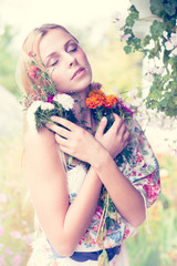 Naklejka premium Close up portrait of beautiful blond young woman pretty girl standing under blooming tree