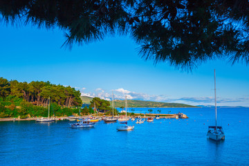 Wonderful romantic summer landscape panorama coastline sea. Boats and yachts in harbor at cristal clear azure water. Green trees at the edge of the coast.