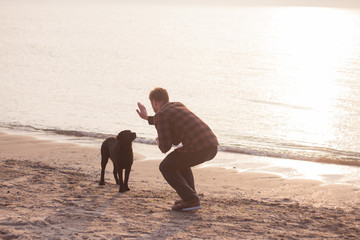 young man make photo of labrador with cellphone morning sea background