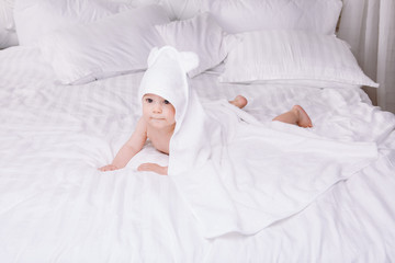 Adorably baby lie on white towel in bed. Happy childhood and healthcare concept.