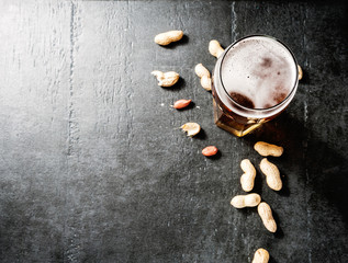 Obraz na płótnie Canvas Glass of beer and snack of peanuts on a concrete table