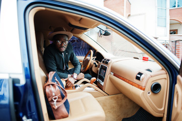 Stylish black man sitting behind the wheel of luxury car. Rich african american businessman.