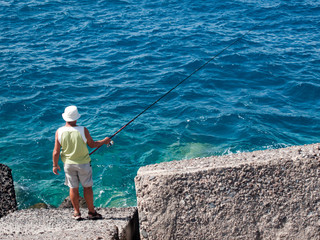 Man fishing in the clear sea water