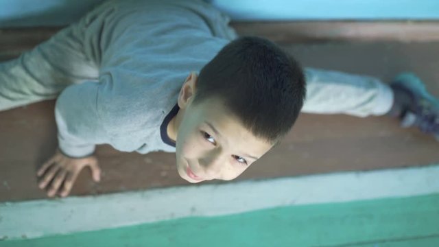 Look of funny young boy lying on the floor and does split in the gym 4K