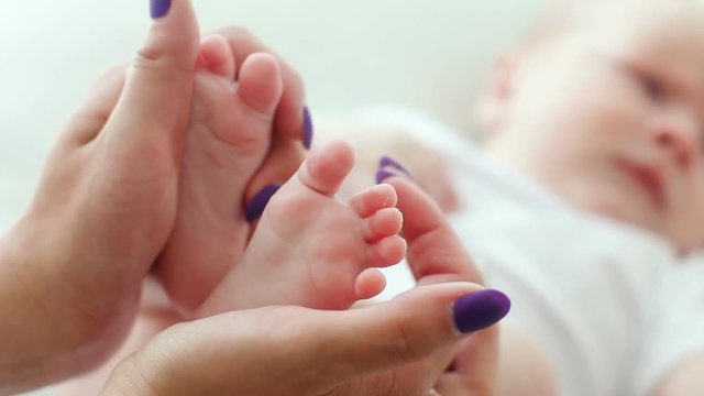 mother holding newborn baby feet and caresses them with his love