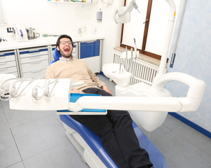 man with open mouth waits sitting in dentist chair in dental sur