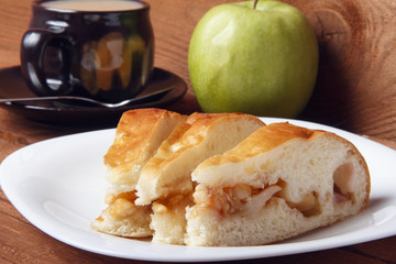 Fresh homemade apple pie and tea with milk on a wooden background