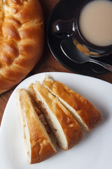 Fresh homemade apple pie and tea with milk on a wooden background
