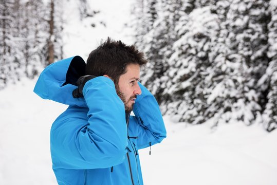 Skier wearing hooded jacket on snowy mountains