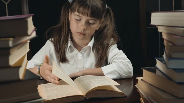 Portrait of eight years thoughtful school girl, reading the book, studying place with books, education concept, 30FPS slide shot