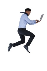 Businessman jumping while using laptop