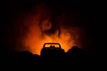 Fototapeta na wymiar silhouette of car with couple inside on dark background with lights and smoke. Romantic scene. Love concept
