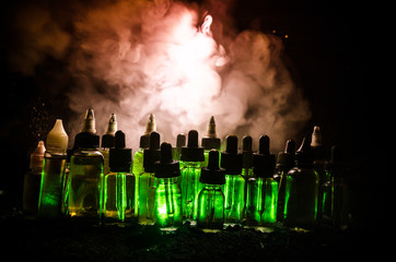 Vape concept. Smoke clouds and vape liquid bottles on dark background. Light effects.