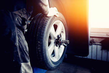 repairman balances the wheel and installs the tubeless tire of the car on the balancer in the...